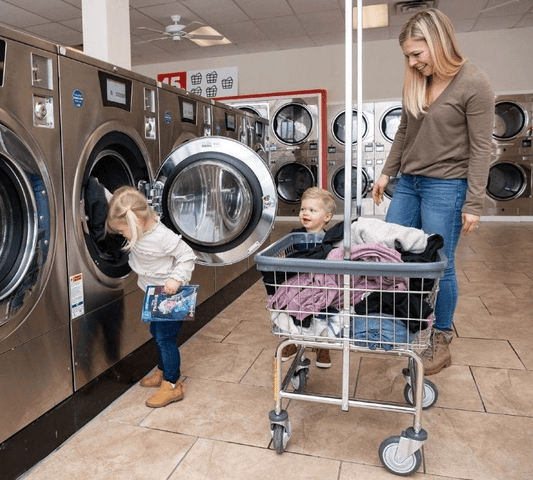 Woman and small children in a laundromat with a wire laundry cart