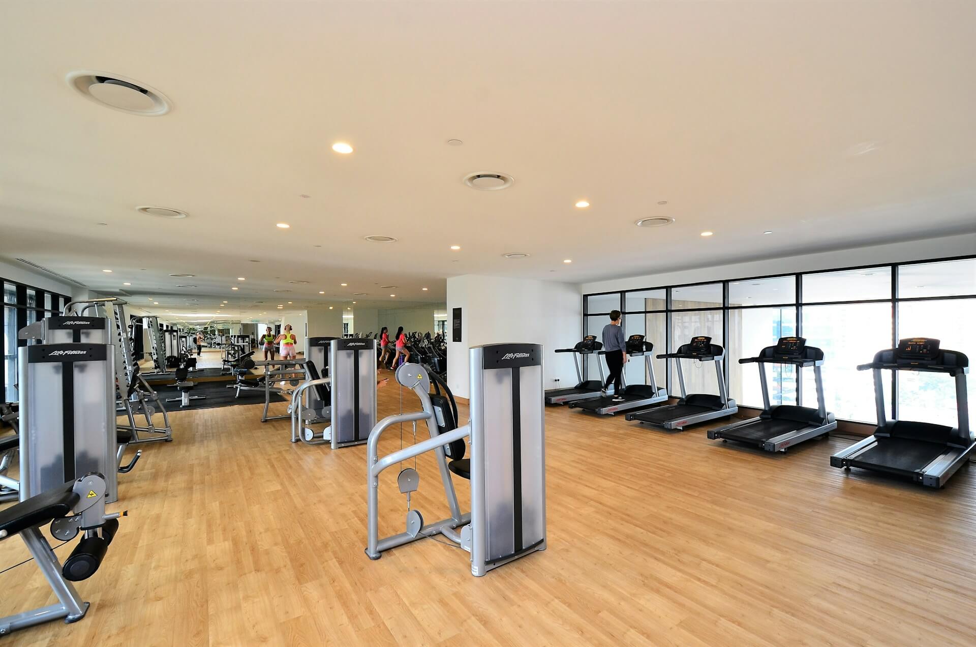 A gym with a row of treadmills and other equipment