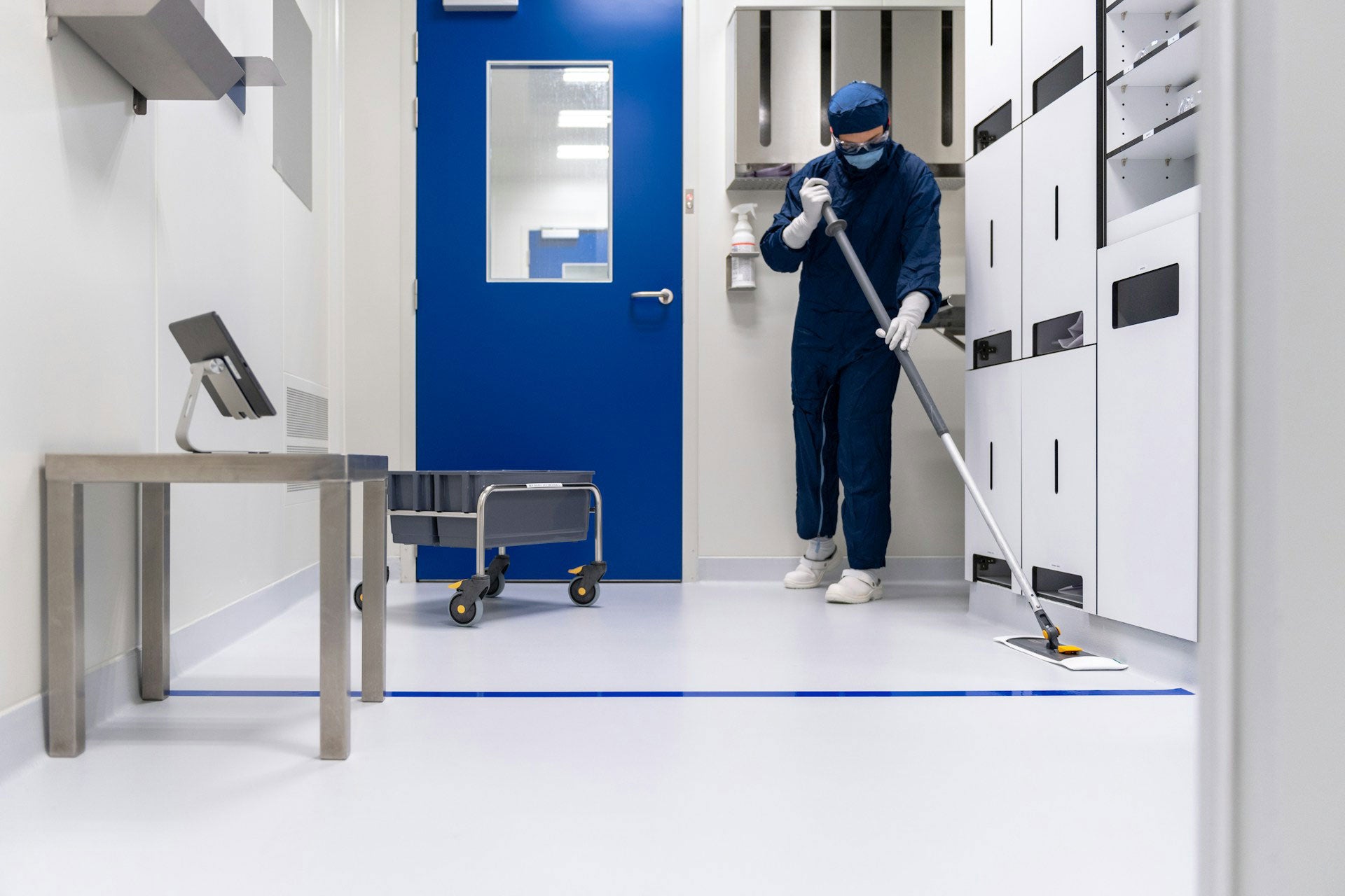 Janitor cleaning the floor in an industrial facility.