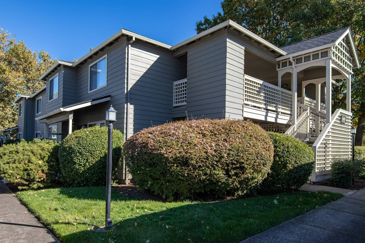 A multi-unit residential property surrounded by bushes.